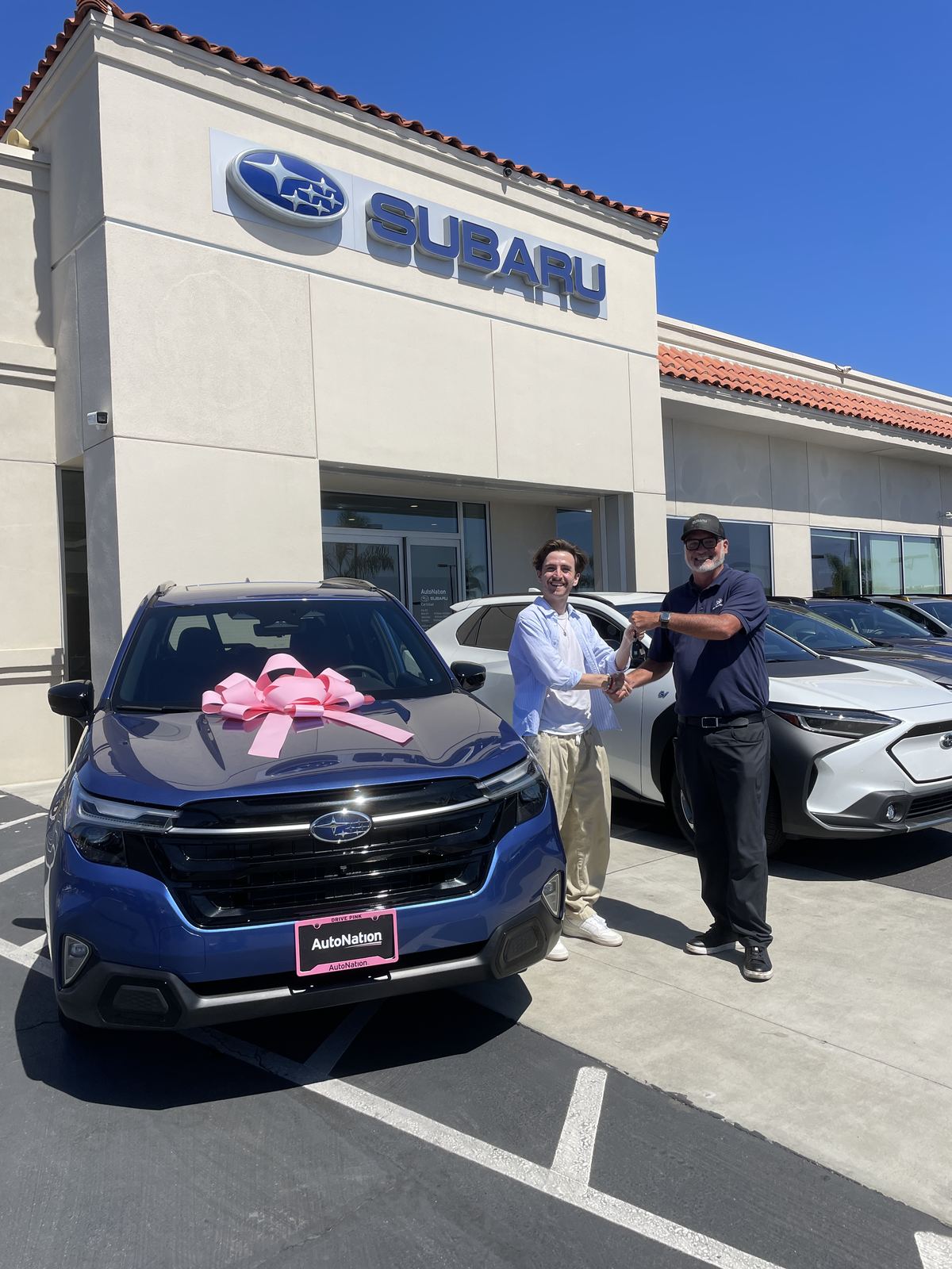 Jake handing over the keys to a brand-new Subaru Forester with a pink bow at the Carlsbad Subaru store